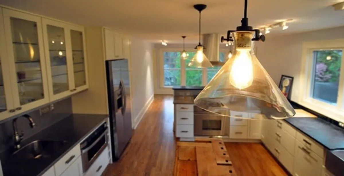 Residential electrician installing modern indoor light fixture in a home in Green Bay, WI
