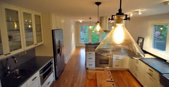 Residential electrician installing modern indoor light fixture in a home in Green Bay, WI